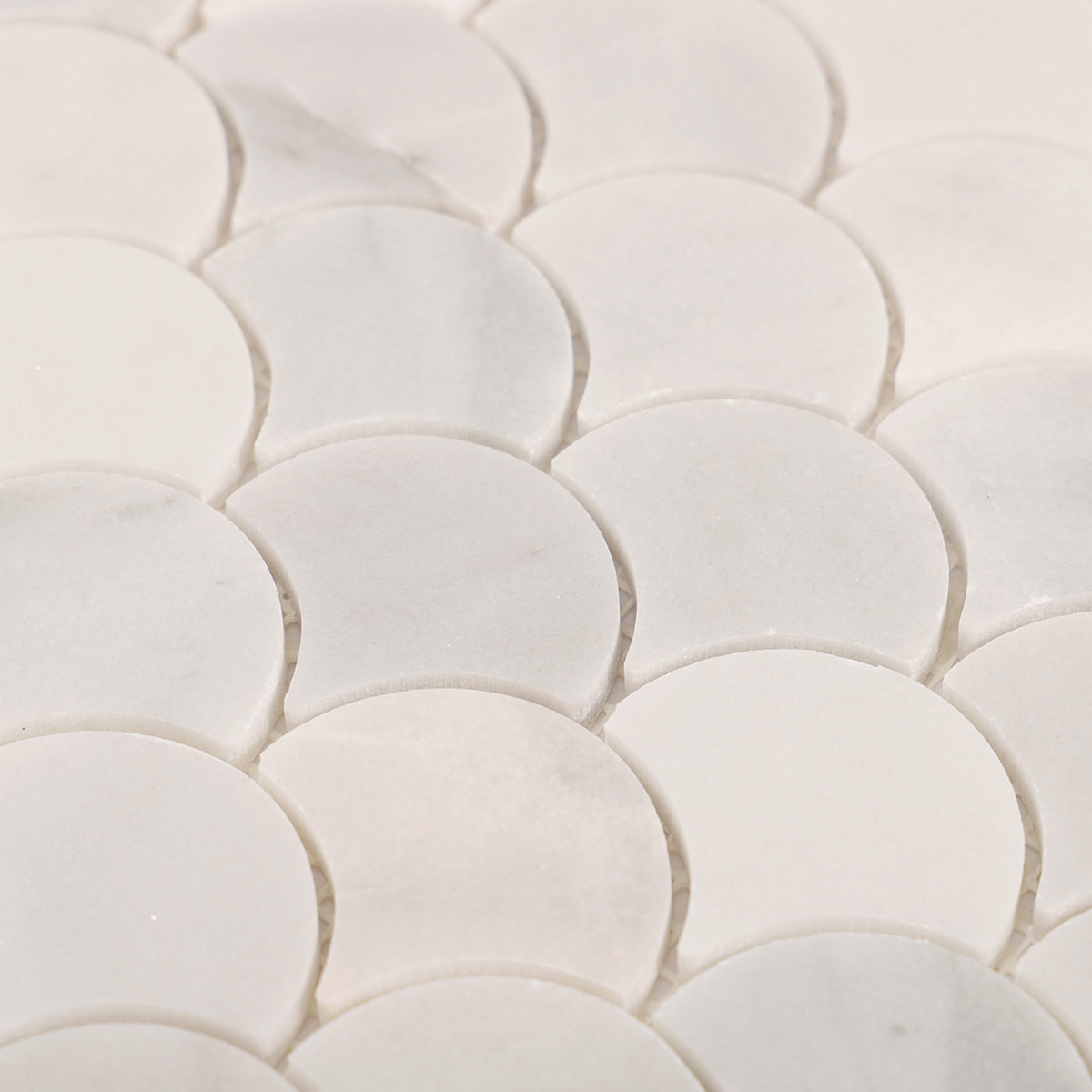 Macro view of white marble fan scallop mosaic tiles highlighting edges and spacing