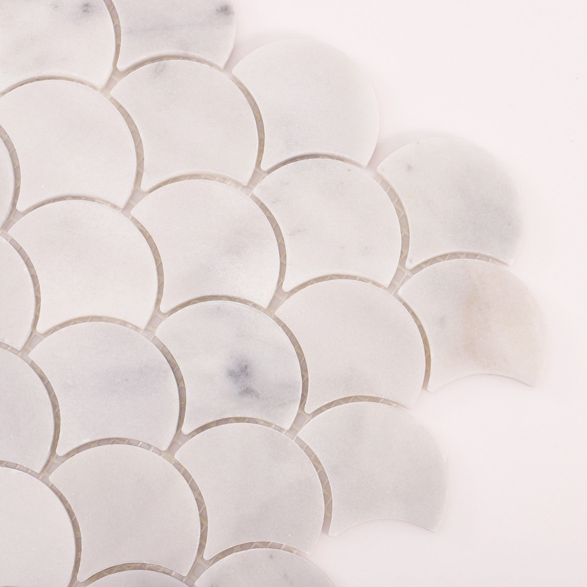 Close up of a corner showing white marble fan scallop mosaic pieces and grout gaps