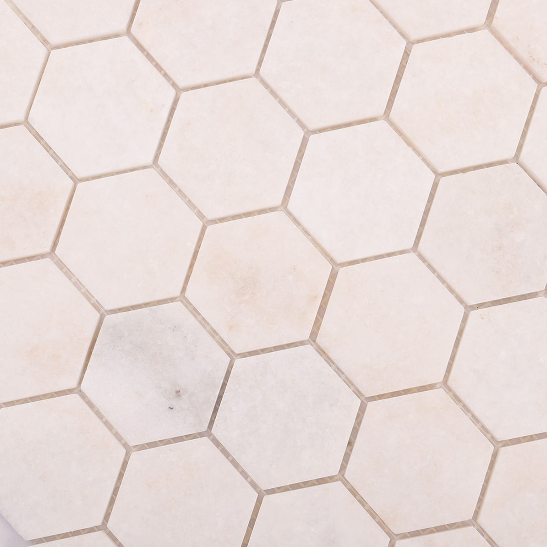 Close-up of white marble hexagon mosaic pattern with natural tone variation.