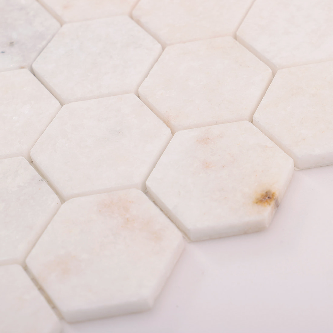 Macro shot showing white marble hexagon tile edges and surface finish.