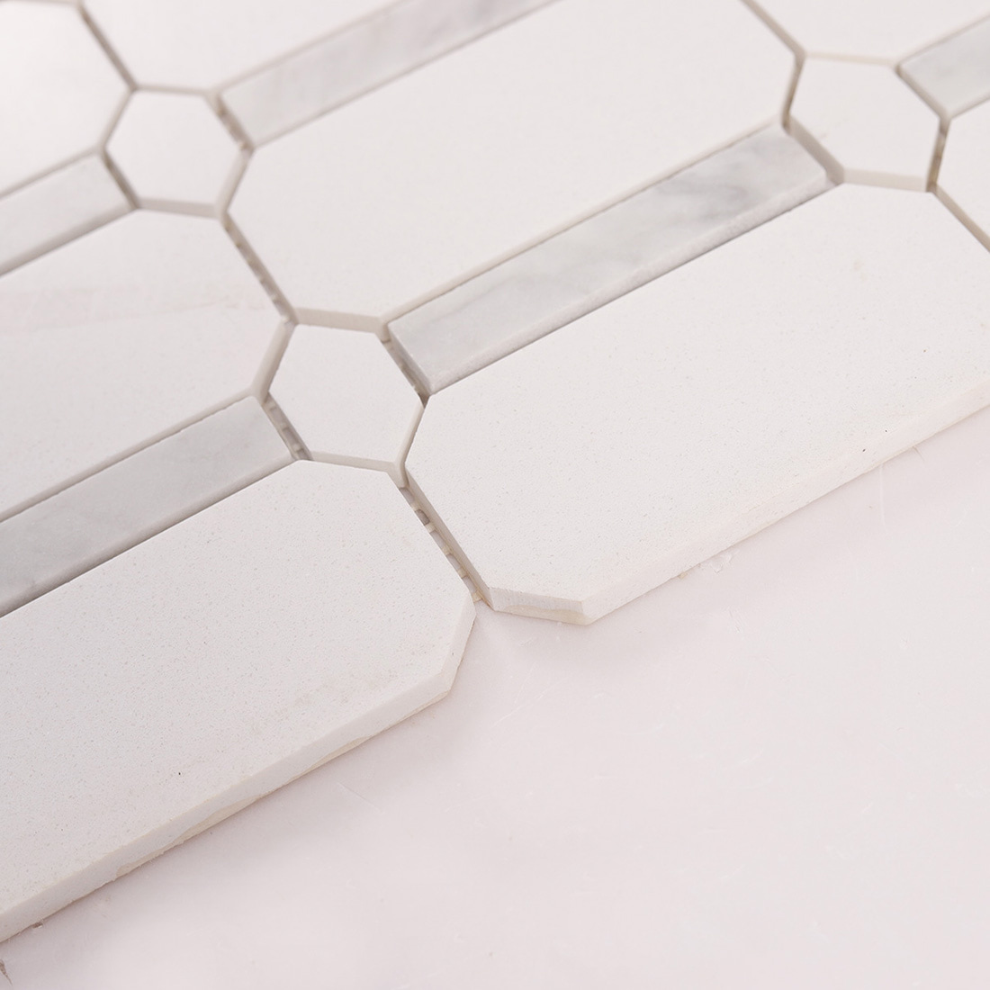 Close up showing thickness of white octagon mosaic tiles and marble strips