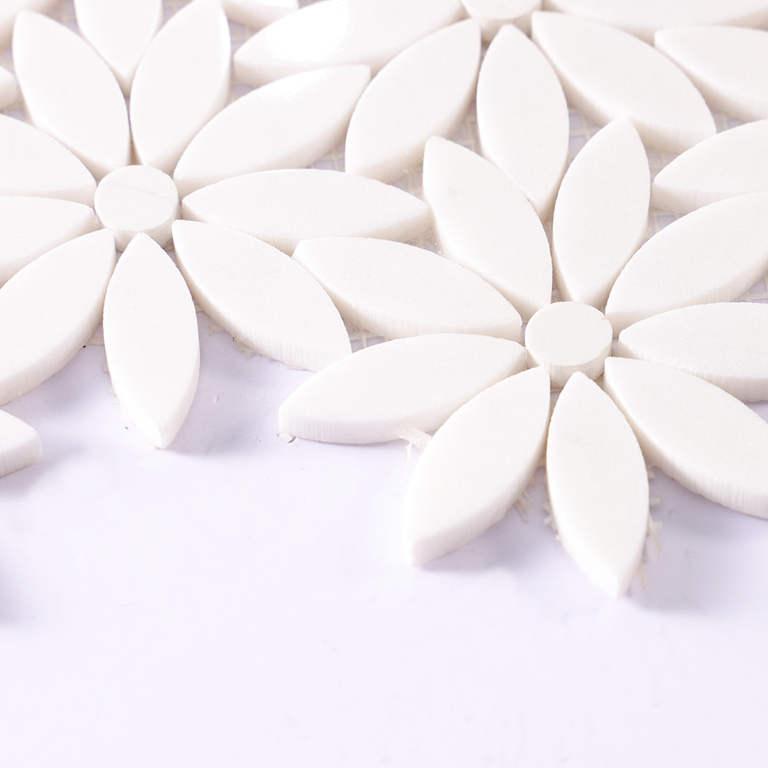 Angled close up showing thickness of white daisy flower mosaic tiles on a sheet