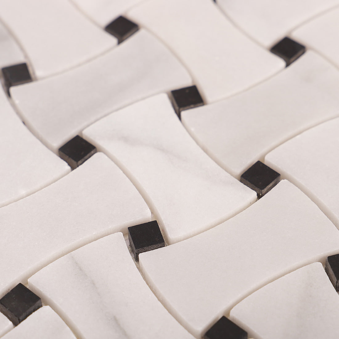Macro view of polished white marble basketweave pieces with black square inserts.