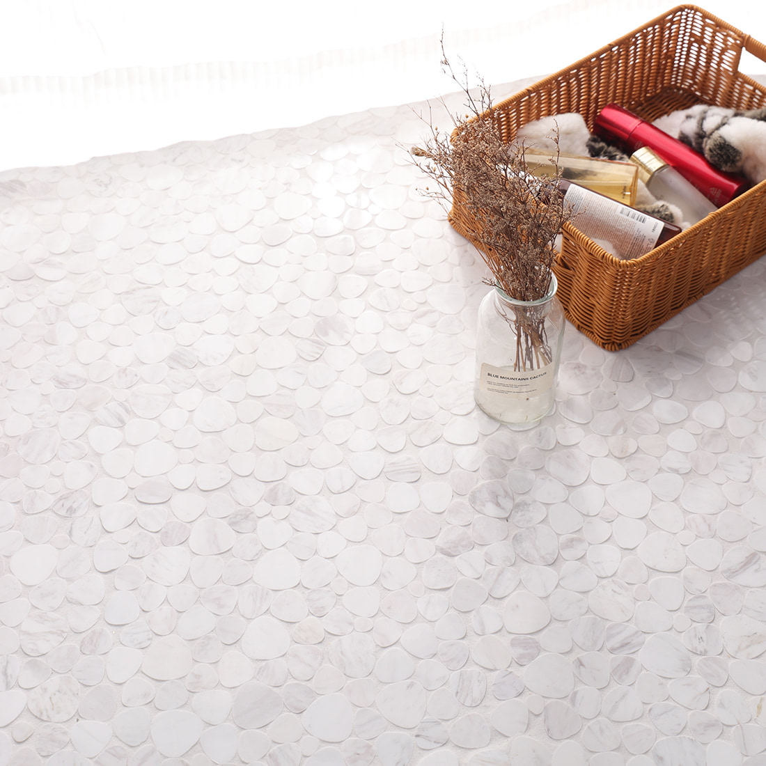 White pebble marble mosaic tile floor styled with basket and bottles