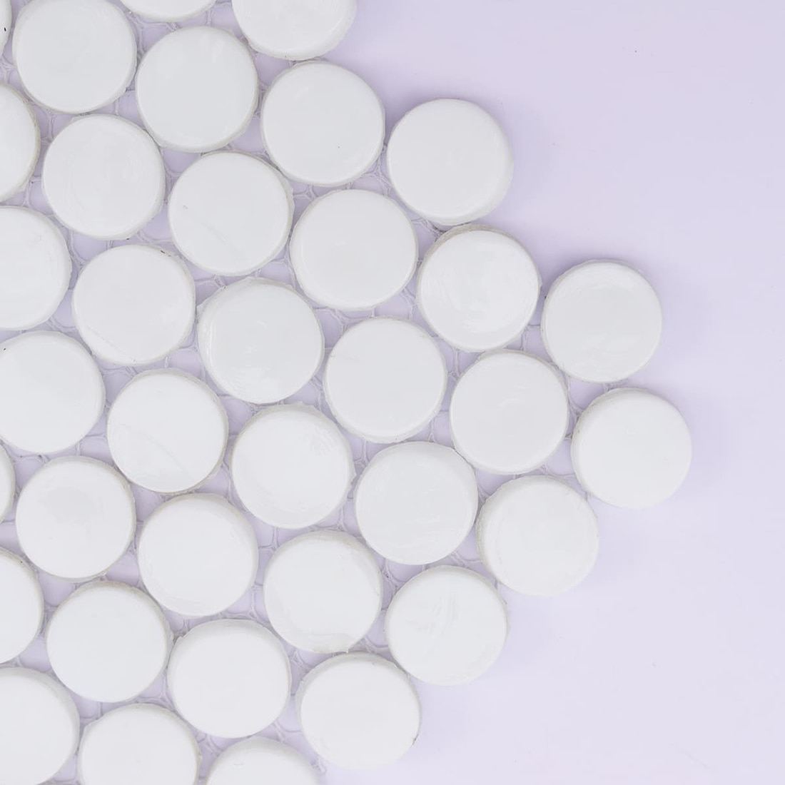 Close-up of white round ceramic mosaic tile corner on mesh backing