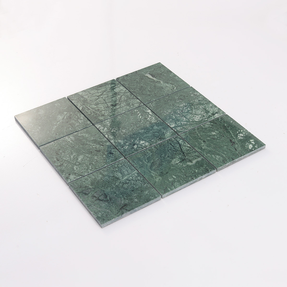 Angled display of dark green marble square tile sheet with visible joints