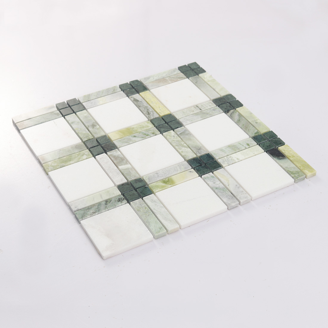 Angled view of green and white marble mosaic tile sheet with framed squares
