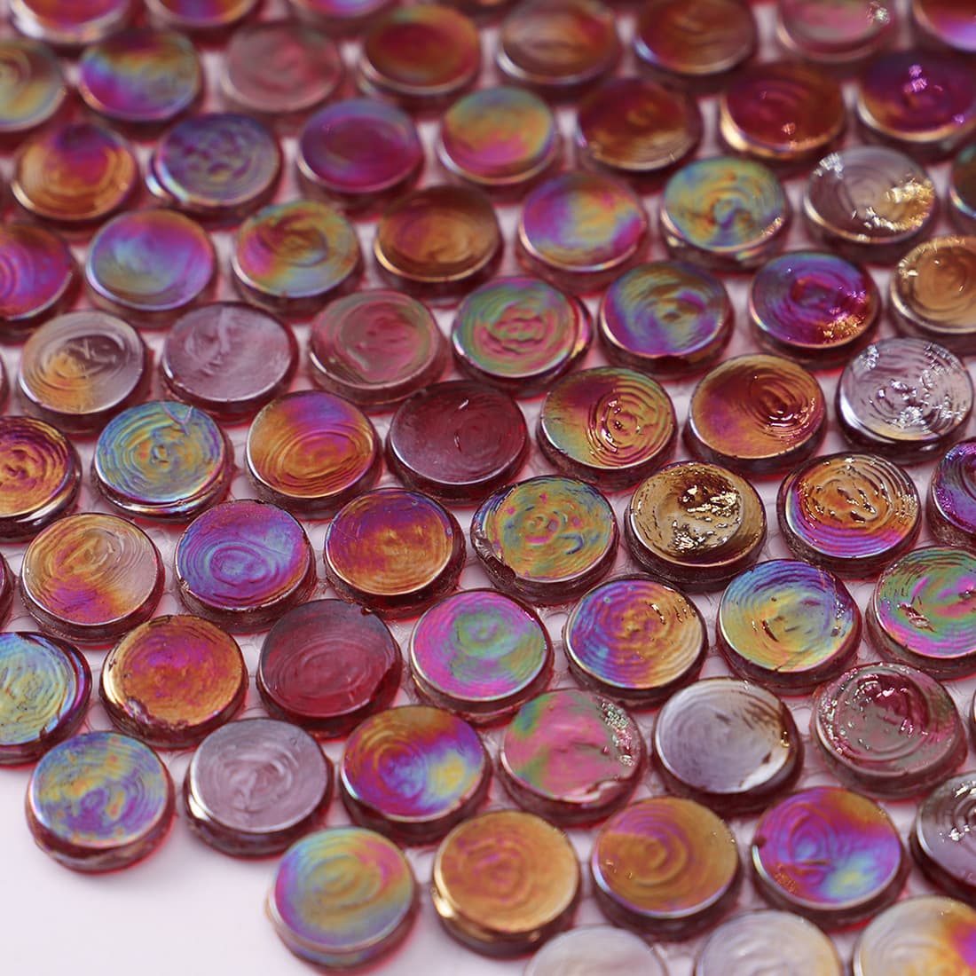 A detailed view of the textured, swirling colors on the surface of iridescent glass penny tiles.