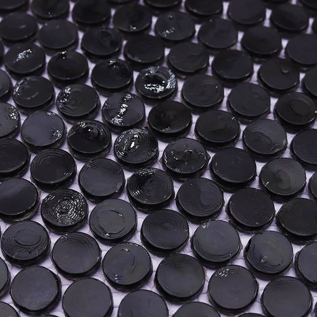 Perspective shot highlighting the reflective surface of black penny round glass tiles.