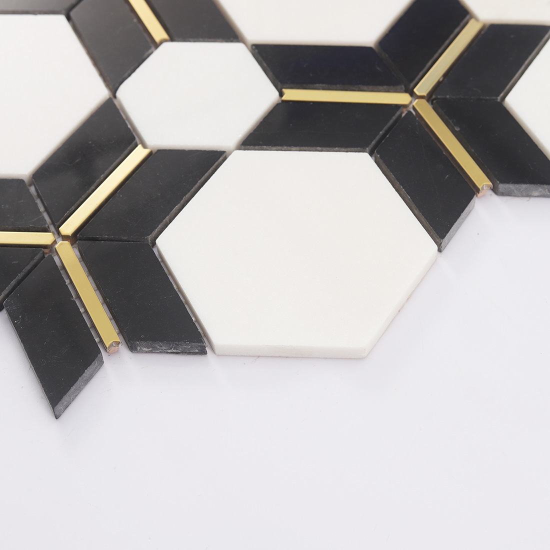 Angled view of white hexagon tile with black geometric pieces and gold strip