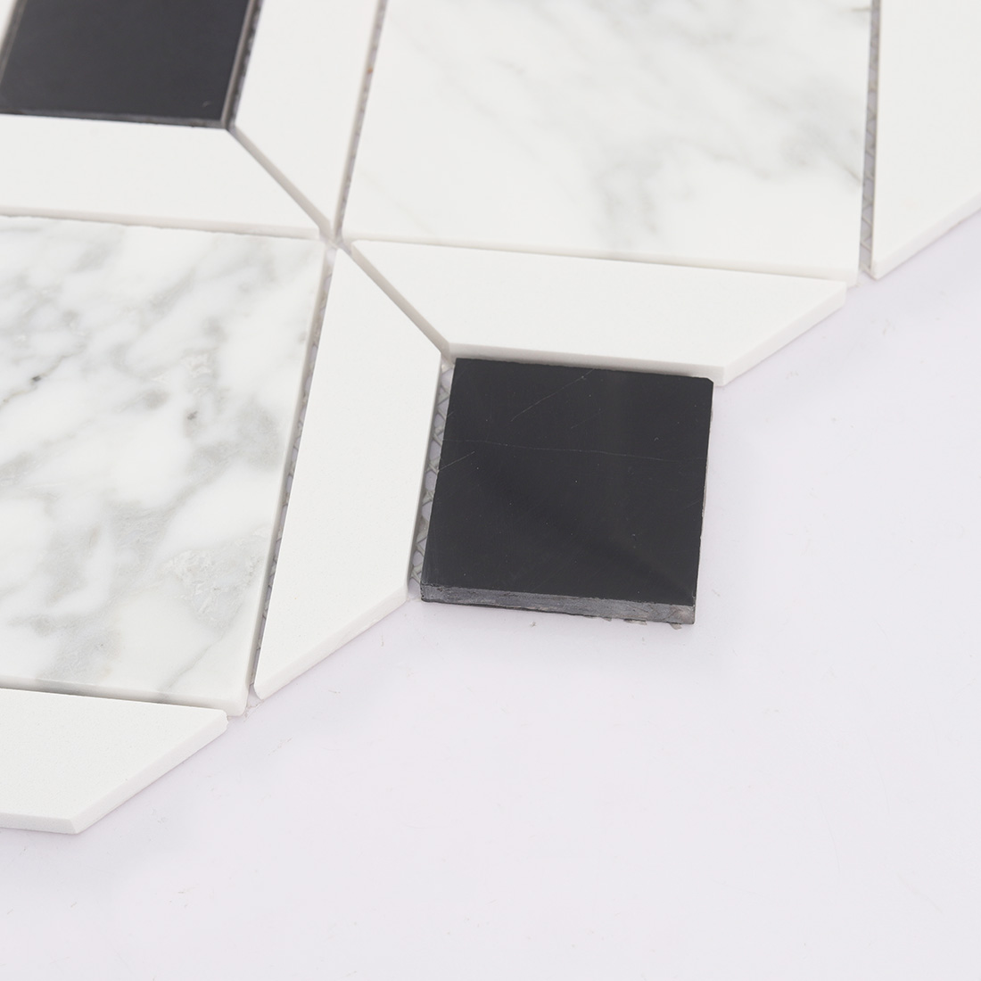 Angled detail of white marble geometric mosaic tile with black square accents