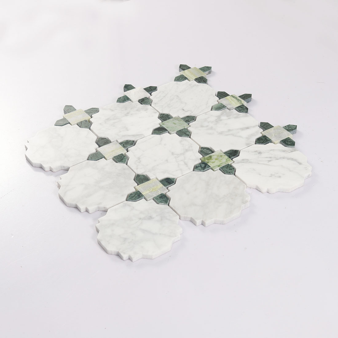 Angled view of white octagon marble mosaic tile with green stone connector pieces