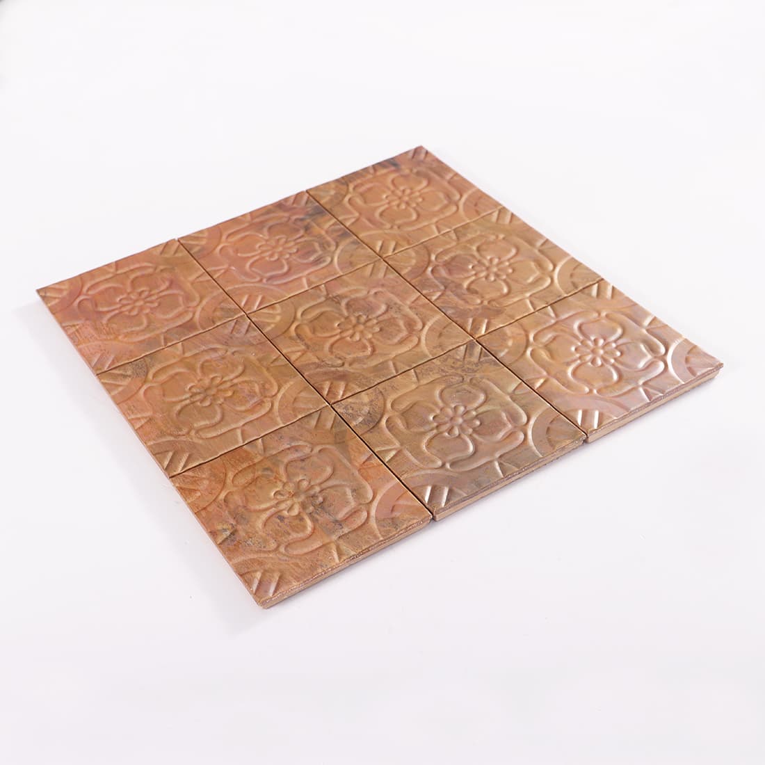 Angled view of antique copper embossed floral mosaic sheet