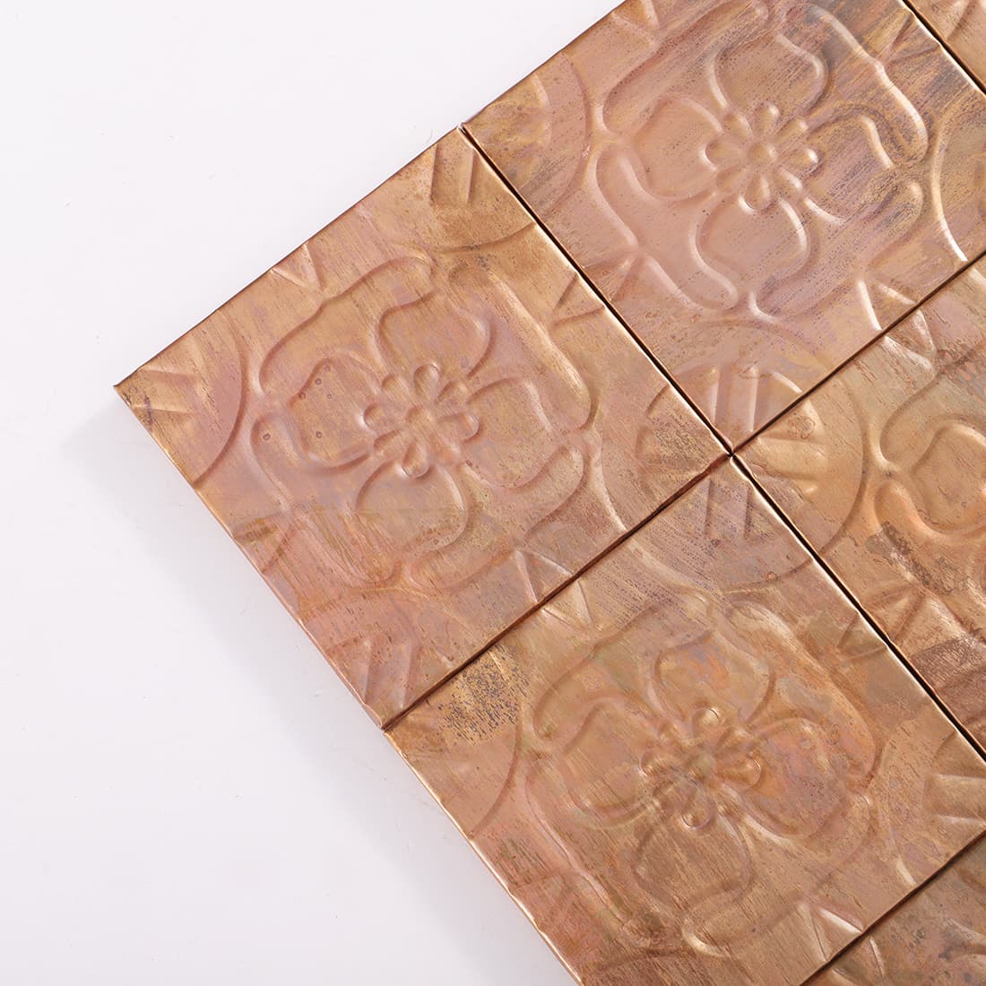 Corner detail of antique copper embossed floral square tiles