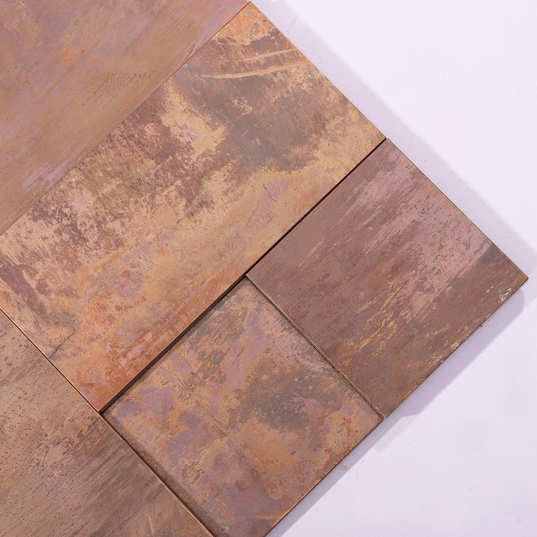 Close-up of antique copper textured metal mosaic tiles in mixed geometric sizes