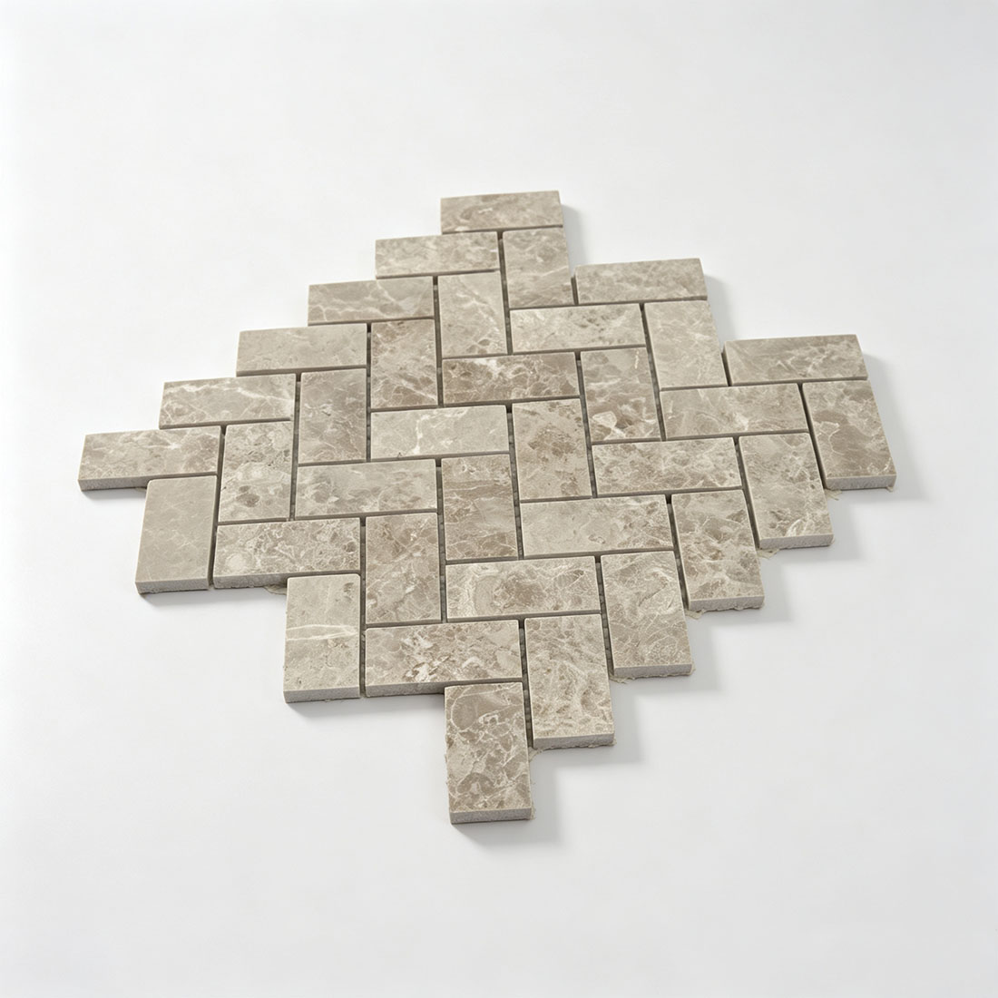 Angled view of beige marble herringbone mosaic tile sheet