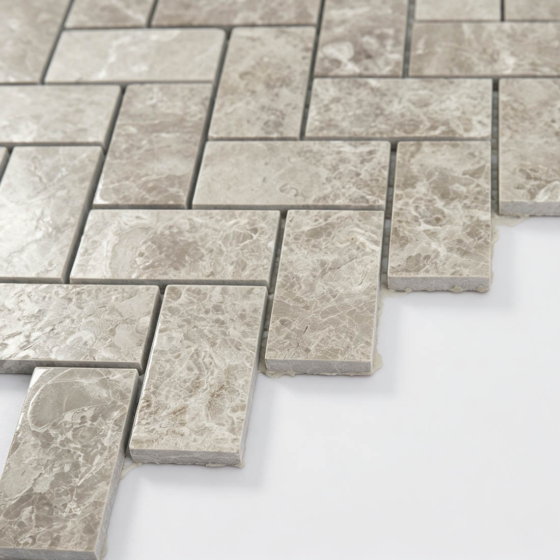 Edge detail of beige marble herringbone mosaic tiles