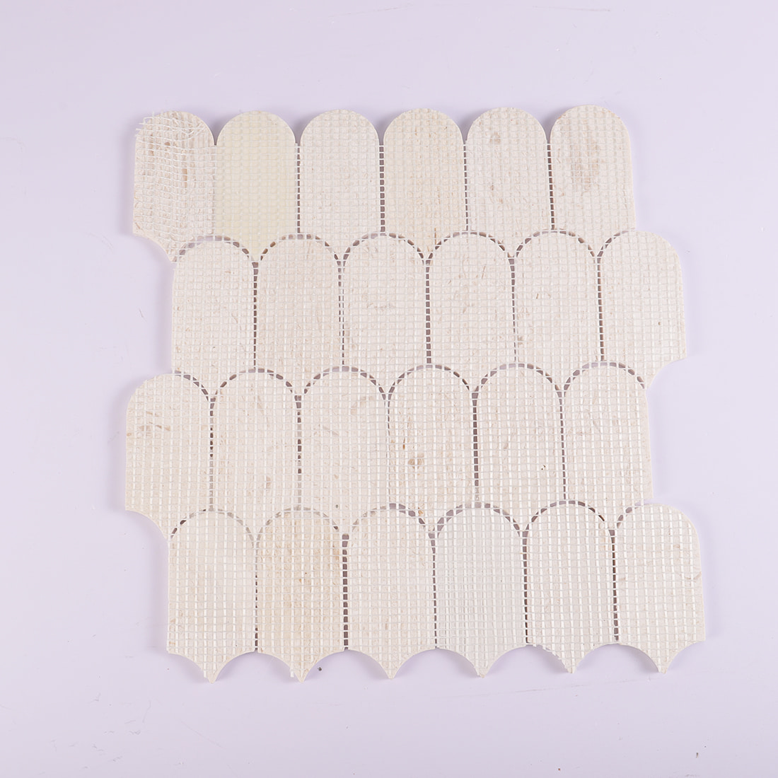 Back view of beige marble scallop mosaic tile with mesh backing