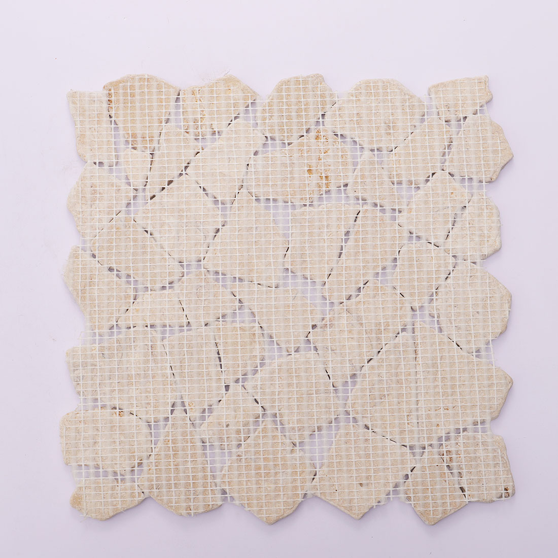 Back view of beige travertine random mosaic tile with mesh backing.