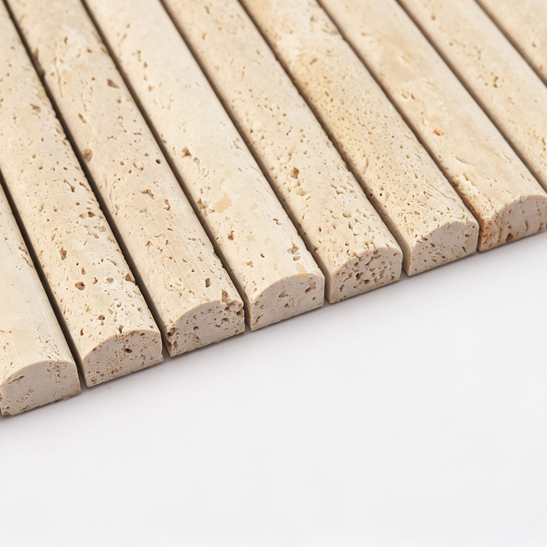 Edge profile of beige travertine rounded bar tile showing curved face