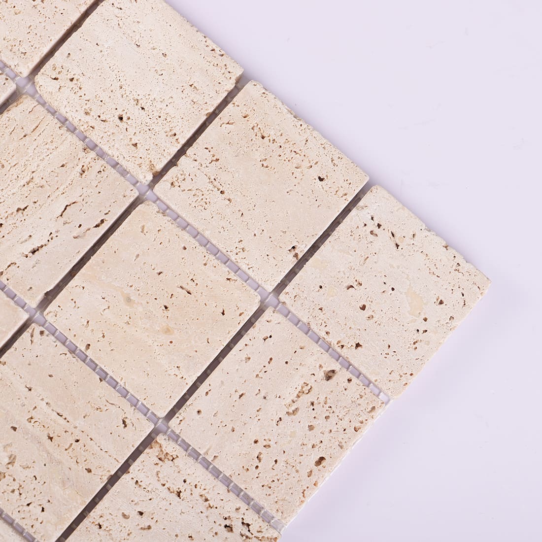 Corner close-up of beige travertine square mosaic tile sheet
