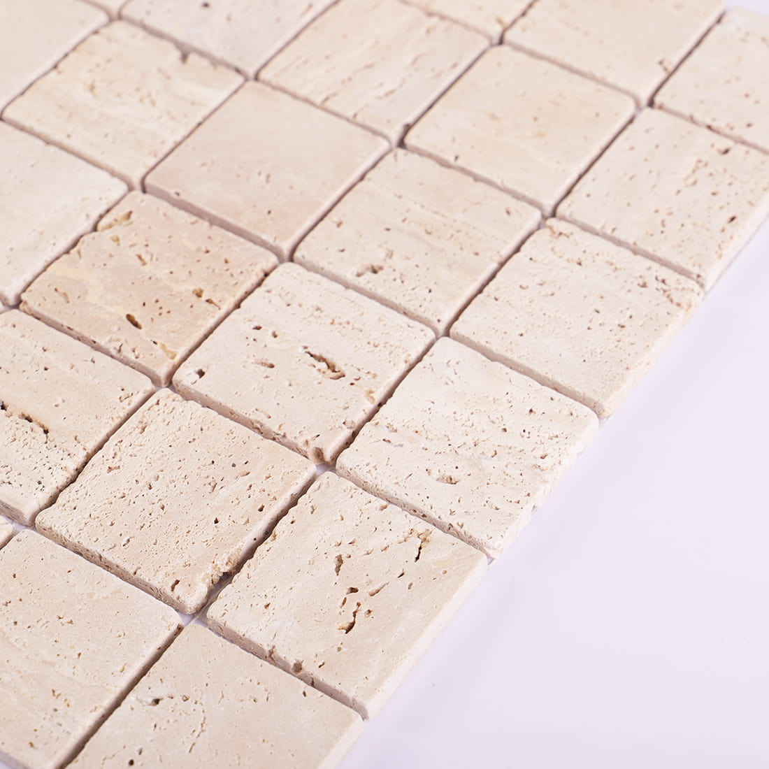 Edge close-up of beige travertine square mosaic tiles