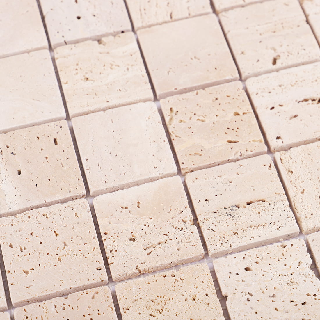 Angled detail of beige travertine square mosaic tiles with natural pores