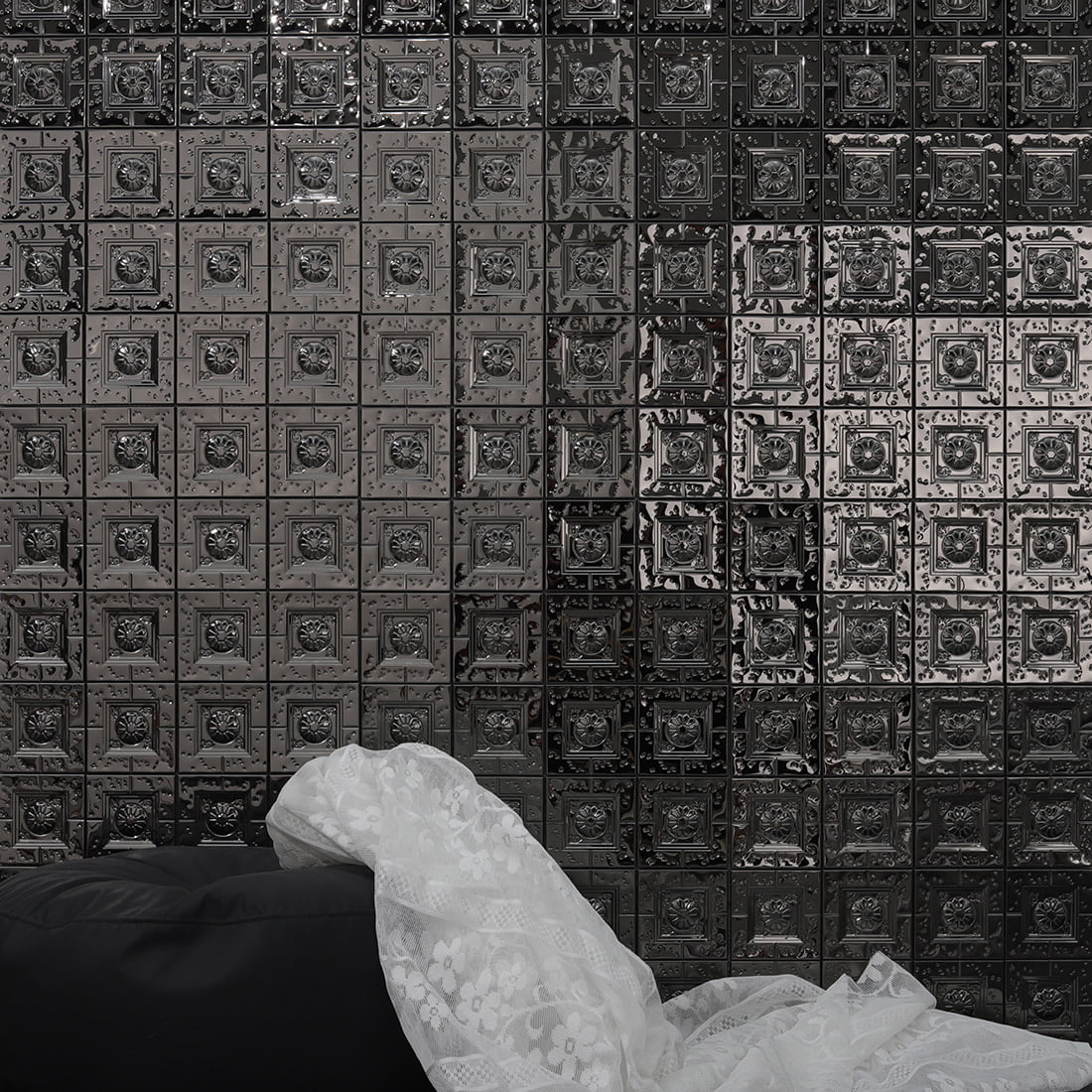 Black embossed square metal mosaic tile wall behind sofa