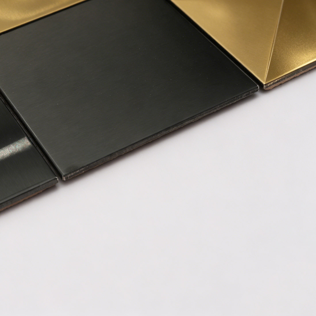 Side detail of black flat square metal mosaic showing tile thickness