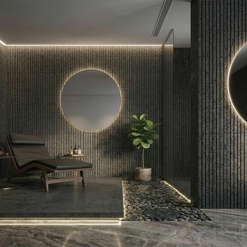Black fluted lava stone wall tiles in a spa room with round mirror and lounge chair