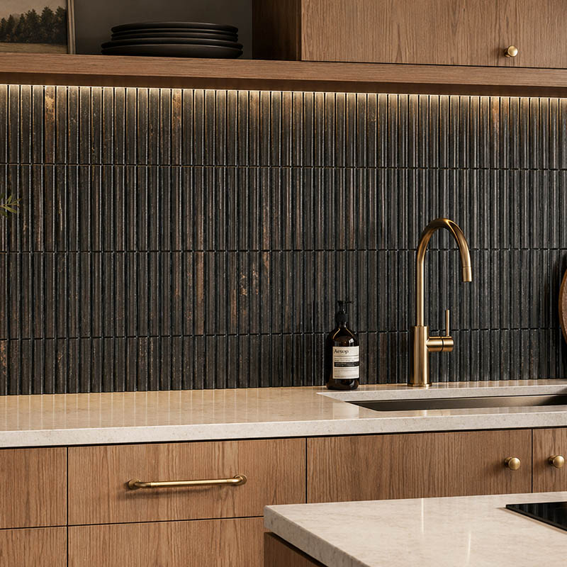 Black fluted tile backsplash with brass faucet and warm wood kitchen cabinets