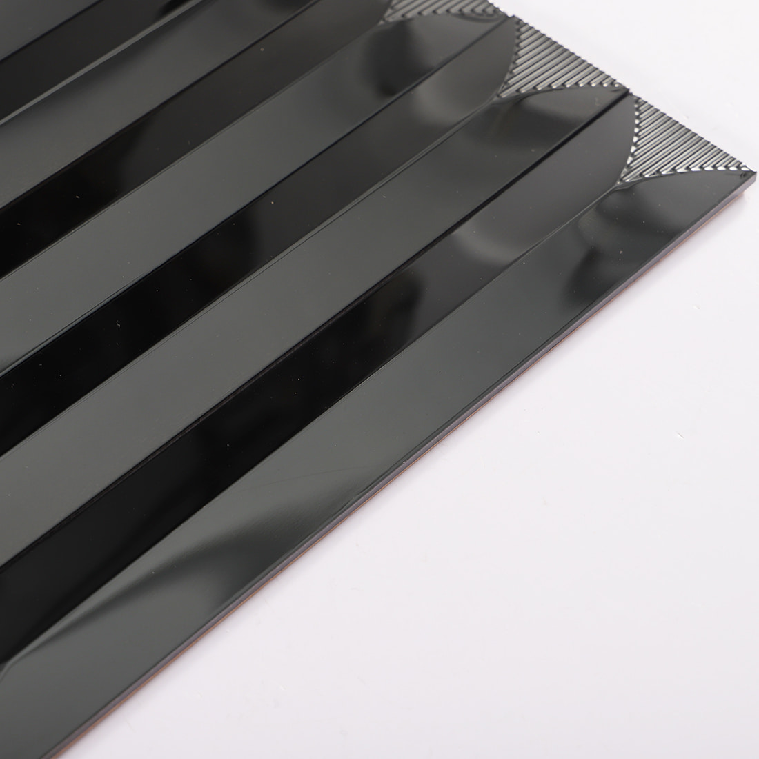 Edge view of black glossy elongated metal mosaic tile sheet