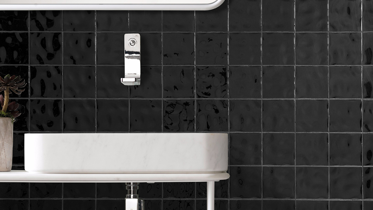 Black glossy square bathroom wall tiles behind a white vanity