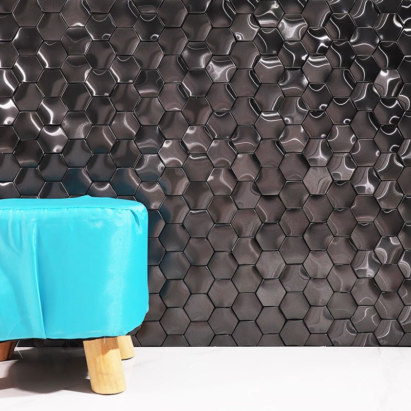 Glossy black hexagon mosaic tile wall behind a turquoise upholstered stool