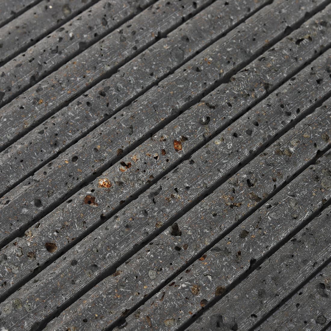 Close-up of black 3D raised lava stone strip mosaic tile surface