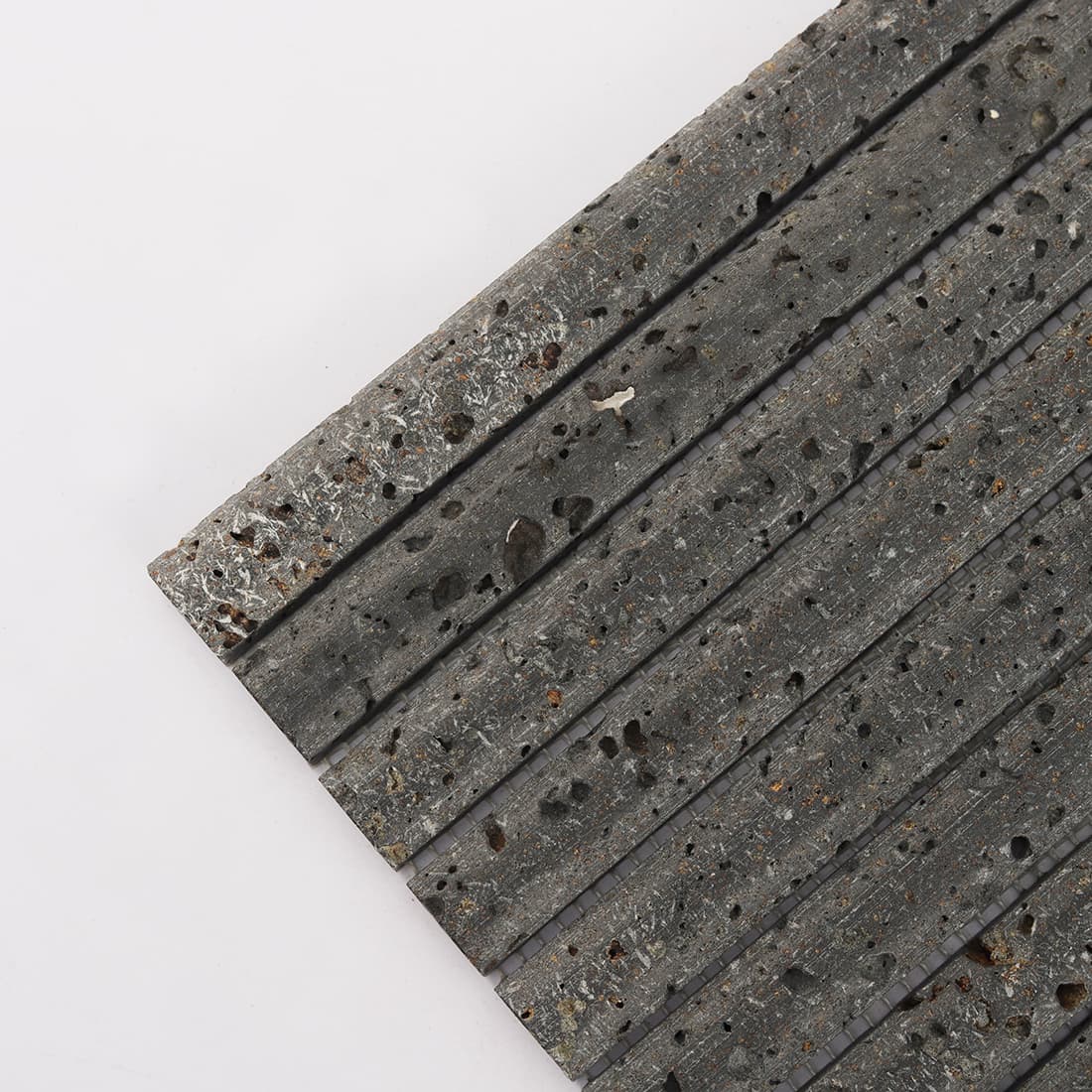 Corner detail of black 3D raised lava stone strip mosaic tile