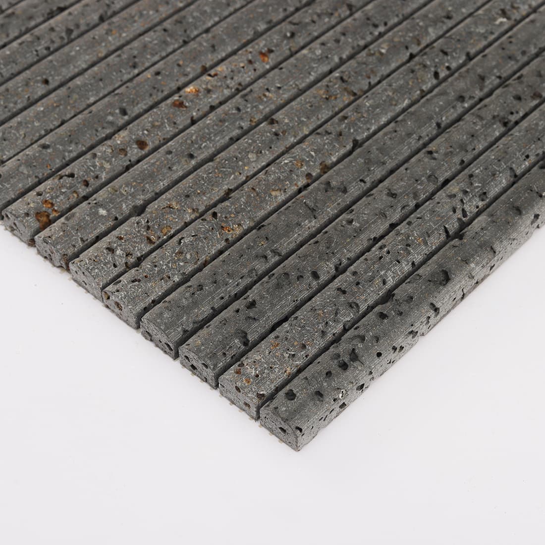 Angled edge view of black 3D raised lava stone strip mosaic tile