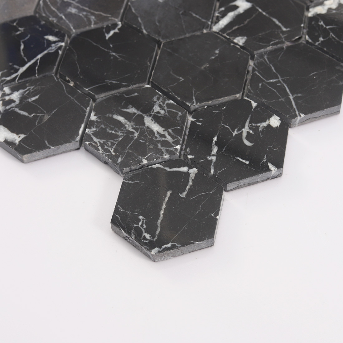 Edge view of black marble hexagon mosaic tile with visible stone thickness