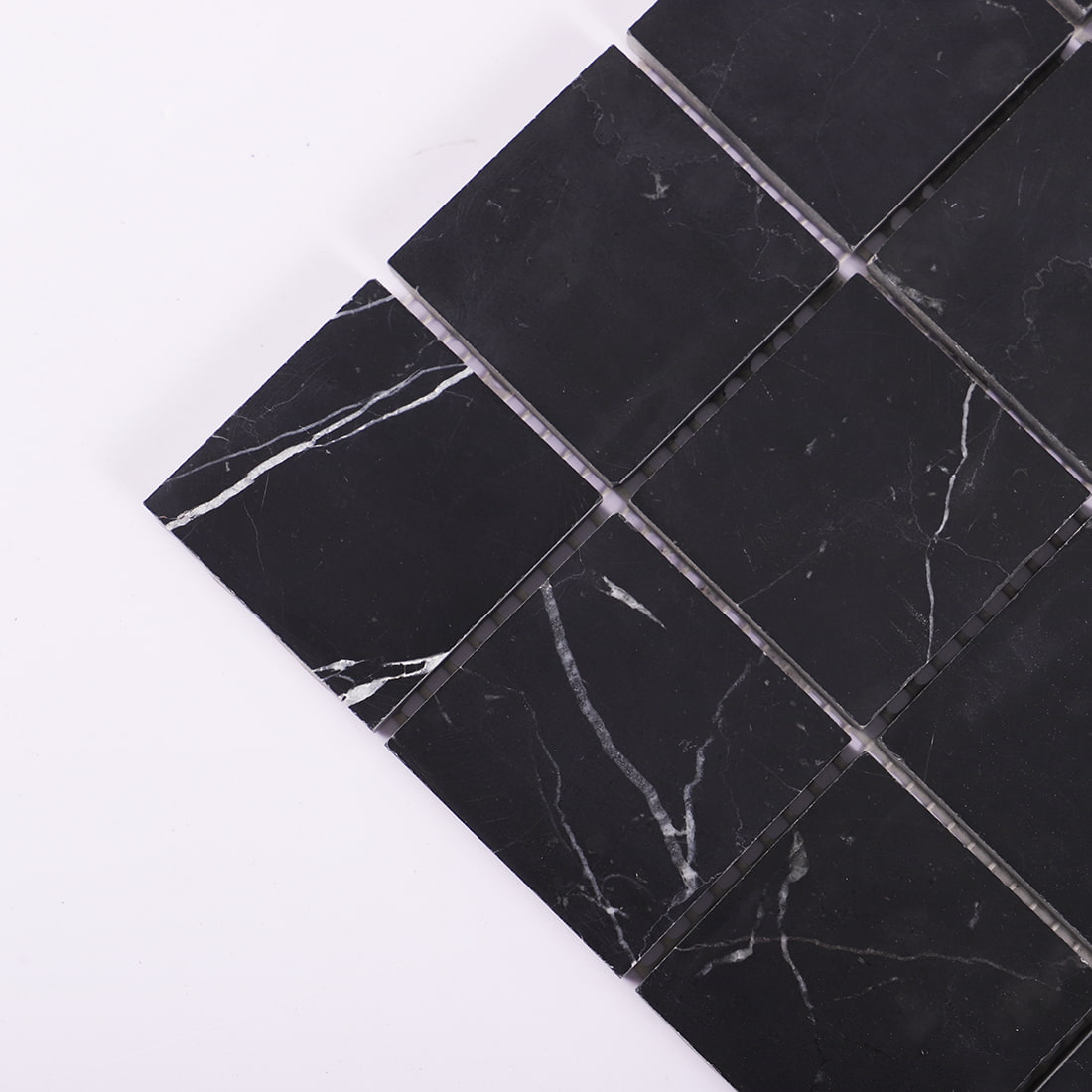 Corner detail of black square marble mosaic tile with natural white veins