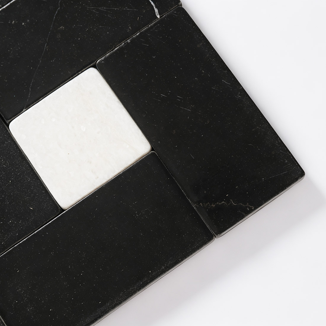 Close-up detail of white square accent on black marble mosaic