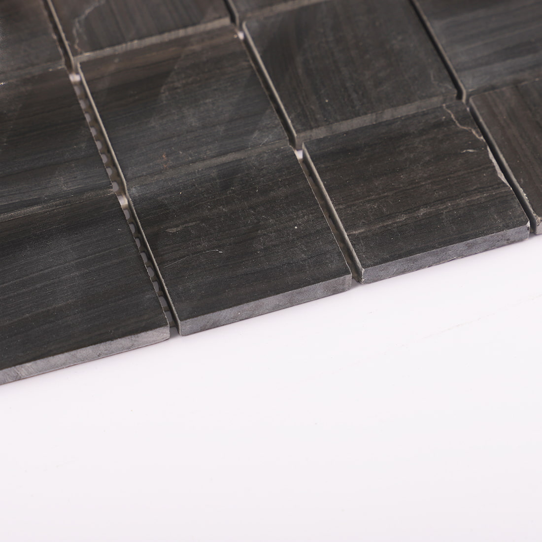Angled edge detail of black square marble mosaic tiles