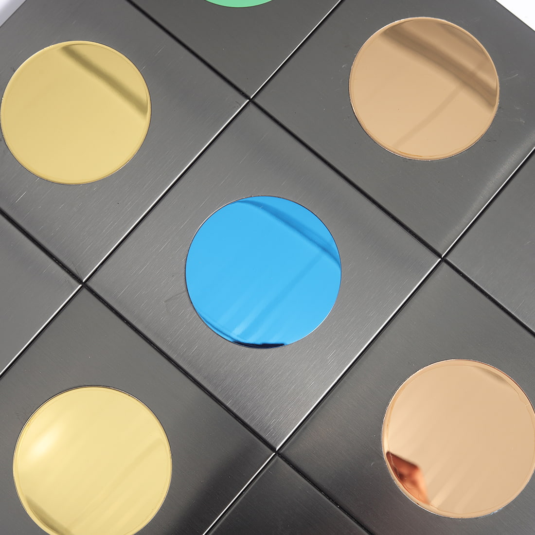 Close view of black square mosaic with blue center and metallic round accents