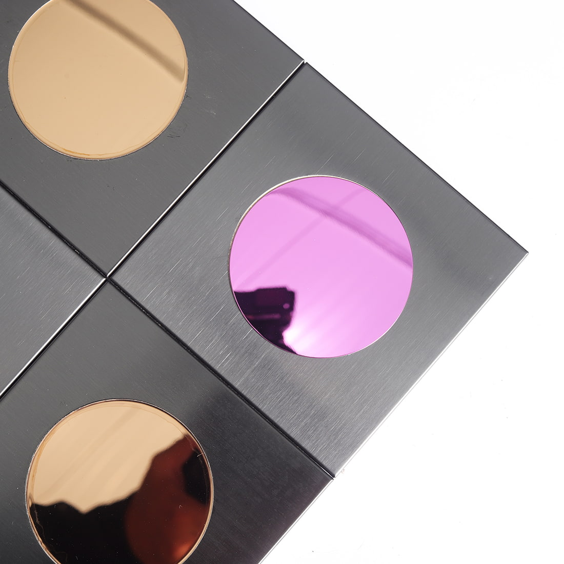 Close up of brushed black square tile with pink reflective round insert