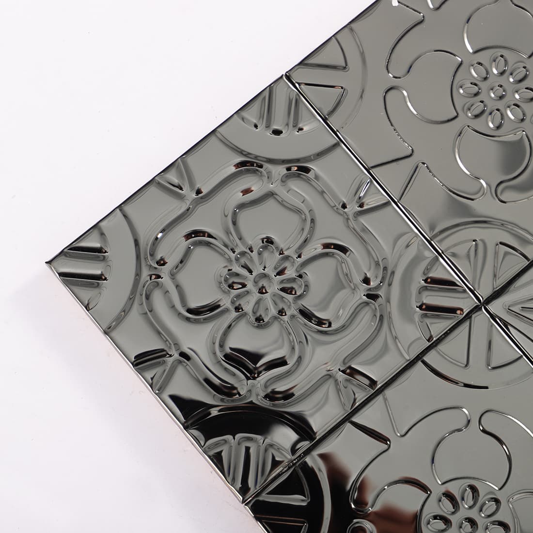 Corner close up of black stainless steel embossed floral mosaic tiles