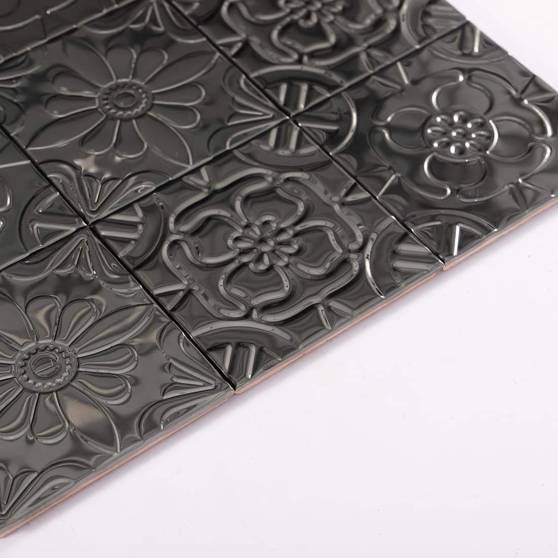 Side view of black stainless steel embossed mosaic tiles showing thickness