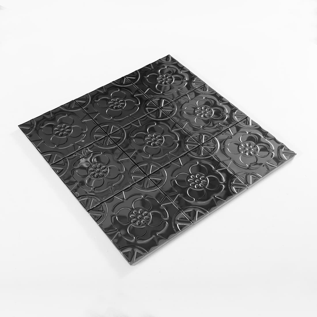 Angled view of black stainless steel floral embossed square tile sheet