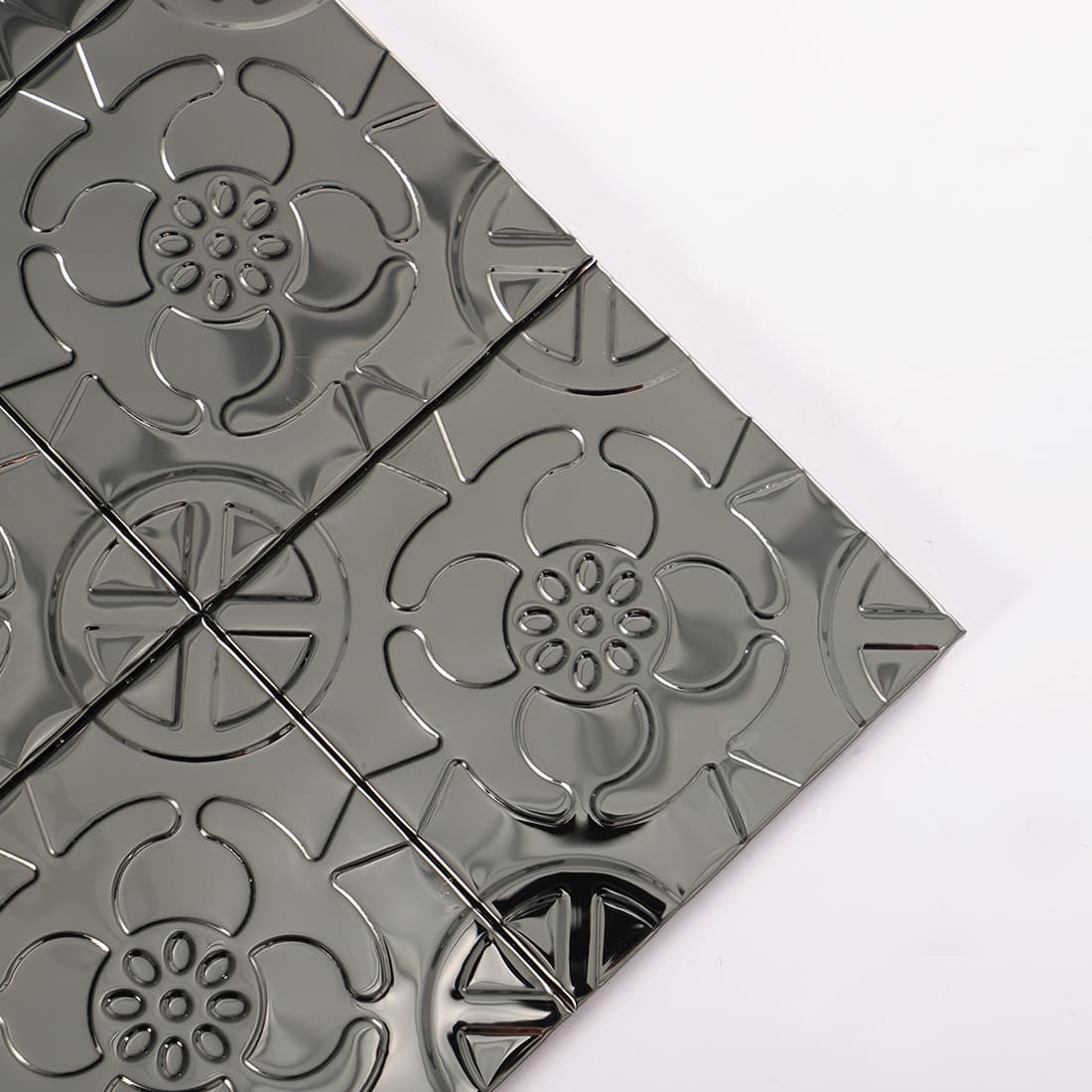 Corner detail of black stainless steel floral embossed square tiles