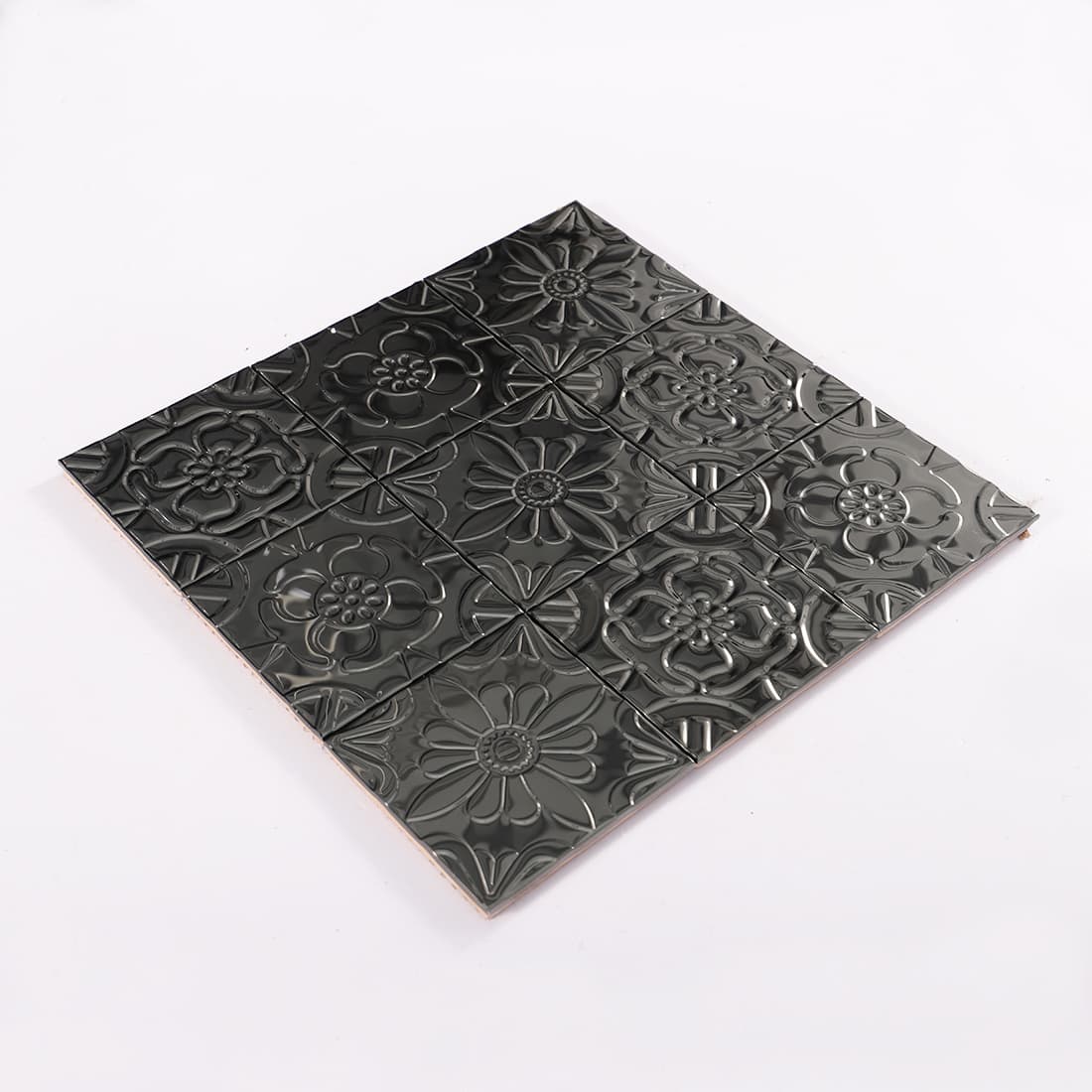 Angled view of black stainless steel mixed floral embossed mosaic sheet