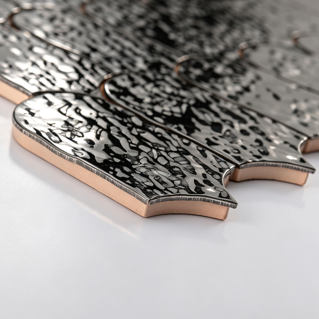 Angle shot of black water ripple arched stainless tile showing edge