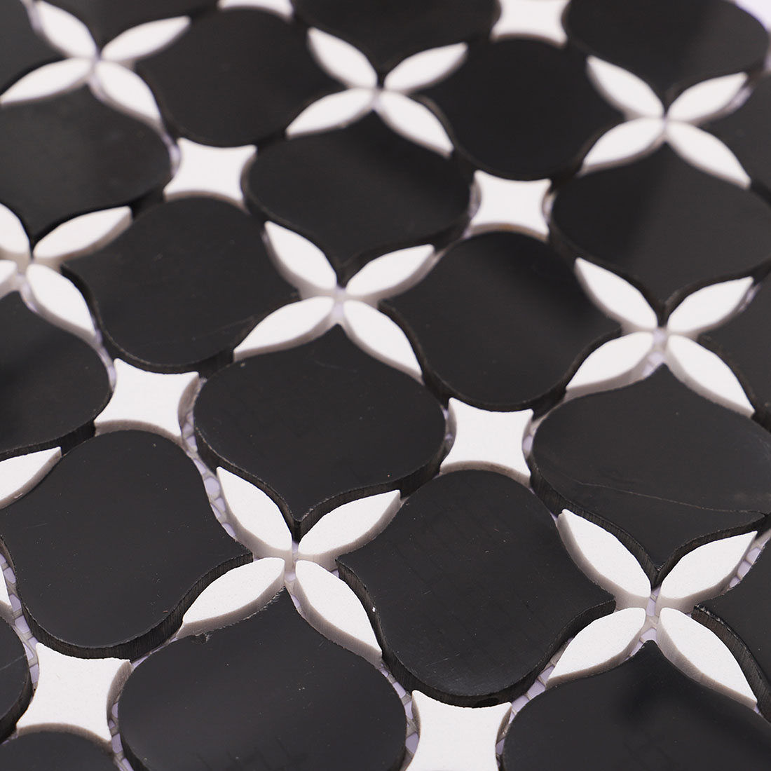 Close-up black and white floral marble mosaic tile with raised surface detail.